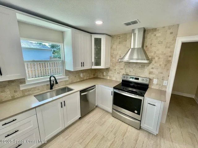 a kitchen with stainless steel appliances a sink a stove and a wooden floors