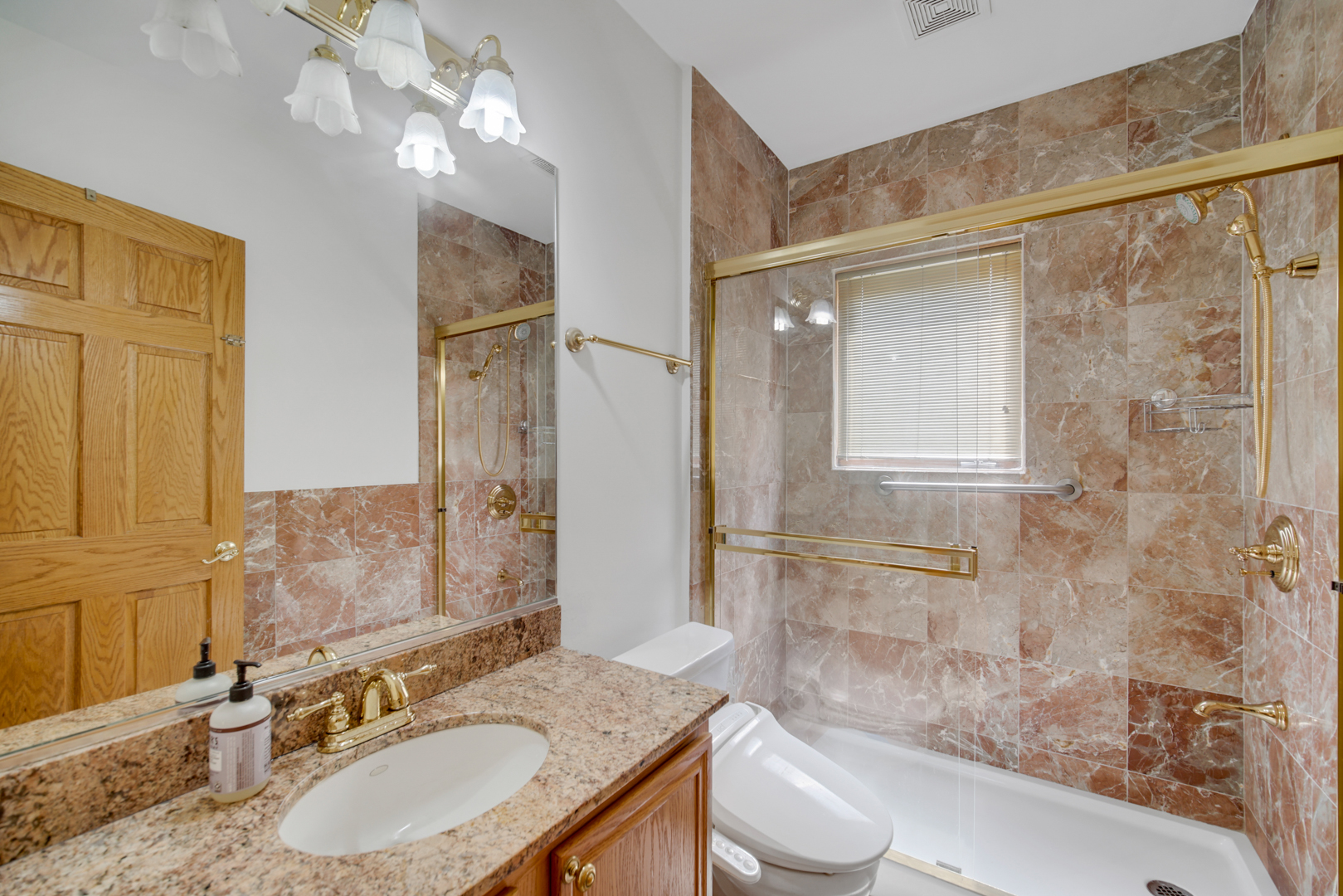 9131 Delphia Street Des Plaines, IL 60016 - Photo 8 of 14 a bathroom with a granite countertop sink toilet a mirror and shower