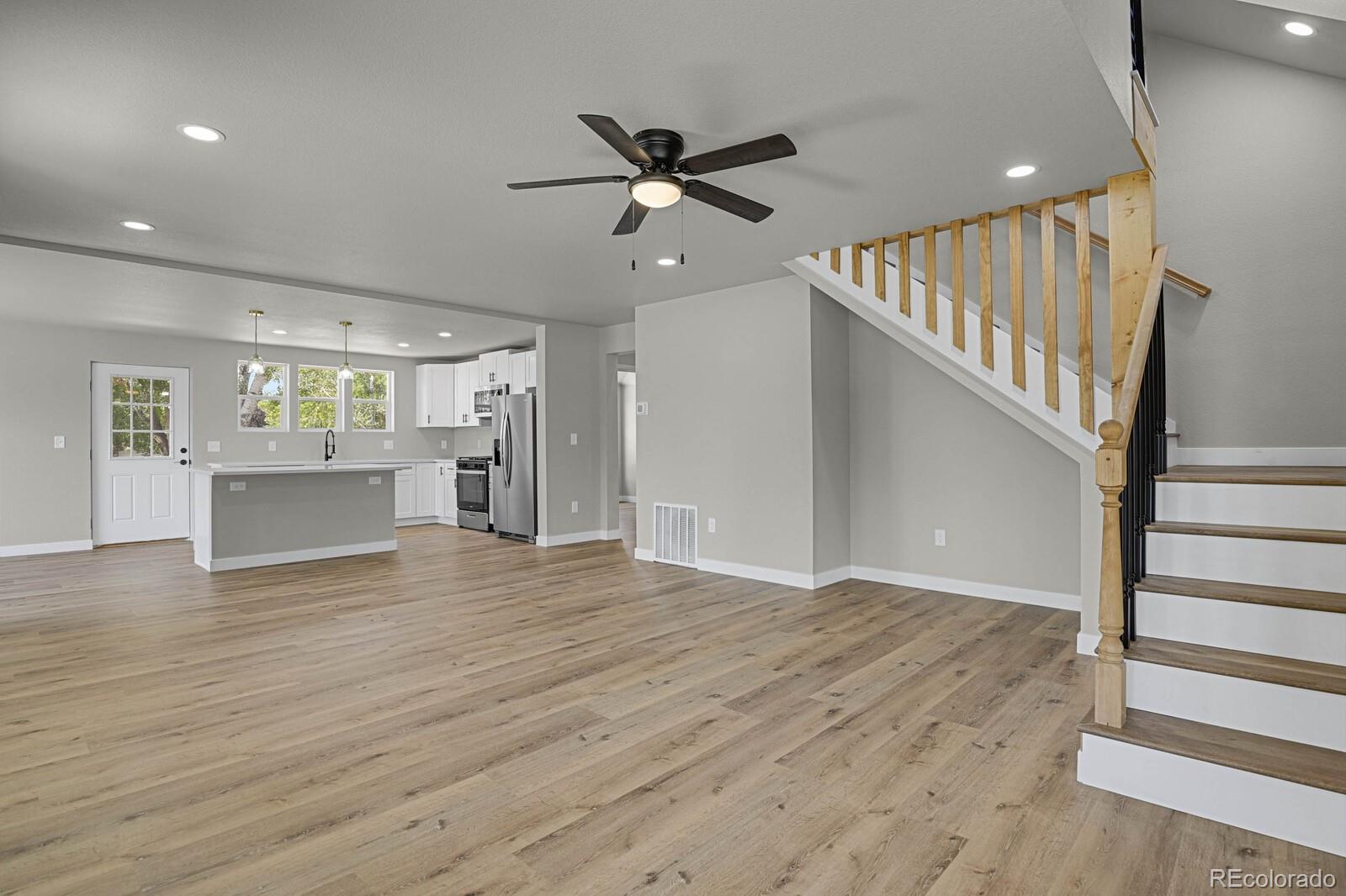 407 Hover Street Longmont, CO 80503 - Photo 6 of 39 a view of an empty room with wooden floor and a ceiling fan
