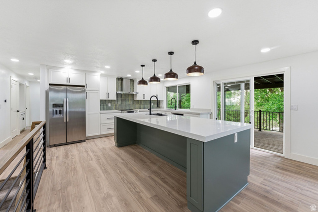 871 Bonita Way Centerville, UT 84014 - Photo 3 of 61 Open-concept kitchen featuring an expansive center island with a light-toned countertop, white cabinetry, stainless steel appliances, and wood-finish flooring