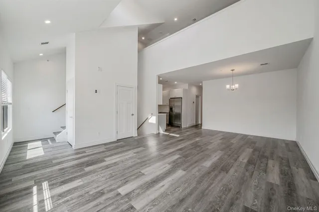 an empty room with wooden floor and entrance to ceiling window