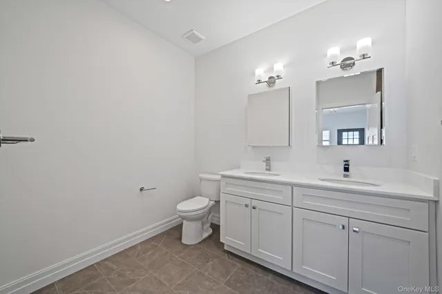 a bathroom with a toilet sink double vanity and mirror