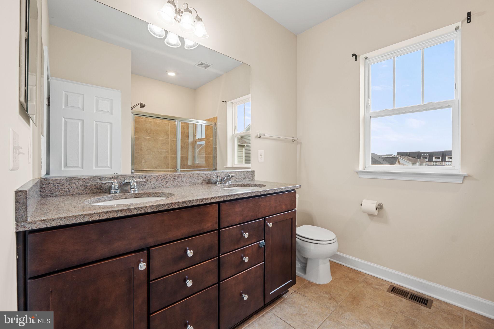 803 Holden Road Frederick, MD 21701 - Photo 30 of 63 a bathroom with a granite countertop sink a toilet and a mirror