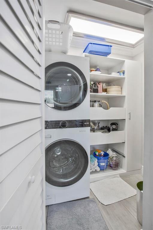 910 Vanderbilt Beach Road, Unit 123W Naples, FL 34108 - Photo 22 of 33 Laundry area featuring stacked washer / dryer and wood-type flooring