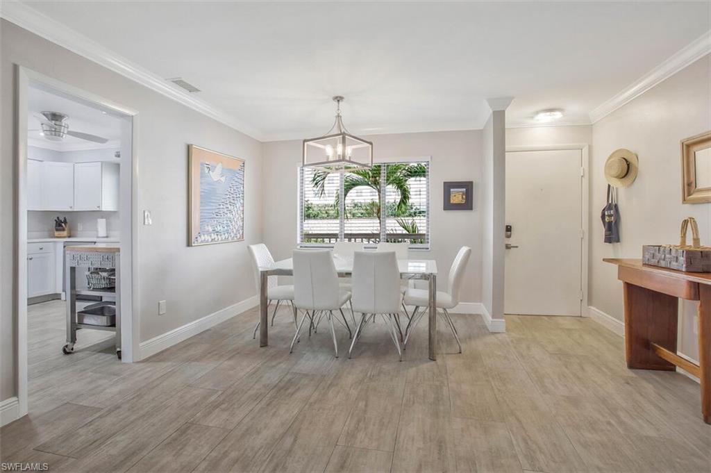 910 Vanderbilt Beach Road, Unit 123W Naples, FL 34108 - Photo 7 of 33 Dining room with light wood-type flooring, crown molding, and a chandelier