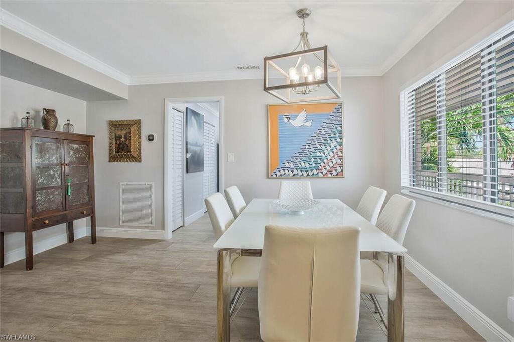 910 Vanderbilt Beach Road, Unit 123W Naples, FL 34108 - Photo 8 of 33 Dining space with light hardwood / wood-style floors, ornamental molding, and a notable chandelier