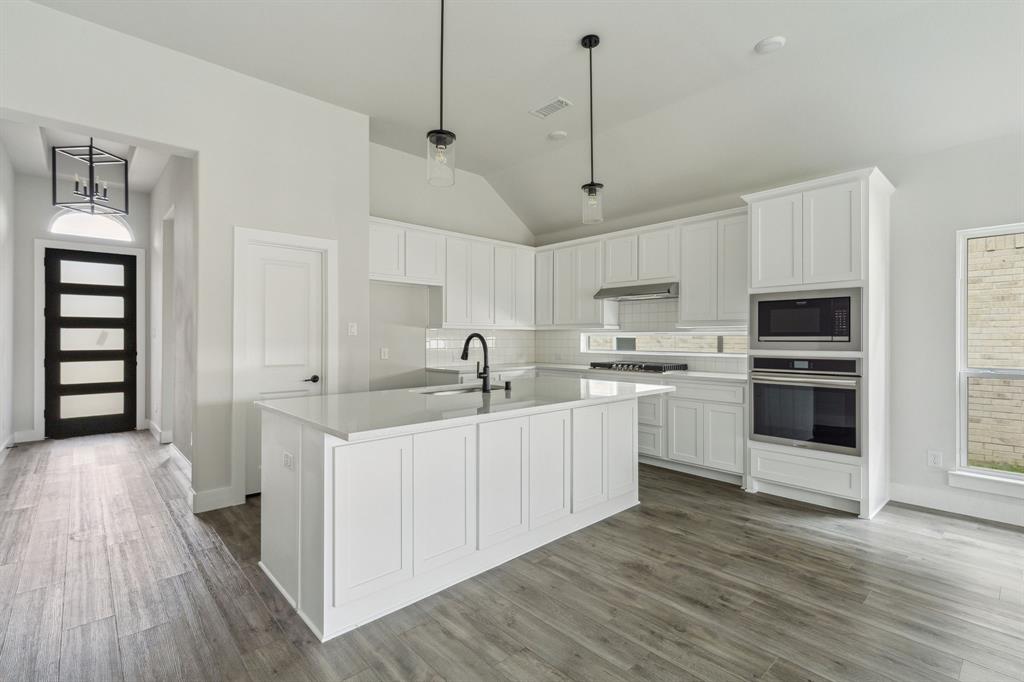 6145 Tahoe Winds Drive Pilot Point, TX 76258 - Photo 4 of 28 a kitchen with white cabinets and stainless steel appliances