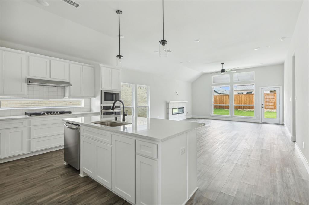 6145 Tahoe Winds Drive Pilot Point, TX 76258 - Photo 7 of 28 a kitchen with stainless steel appliances granite countertop a sink a stove a refrigerator and white cabinets with wooden floor
