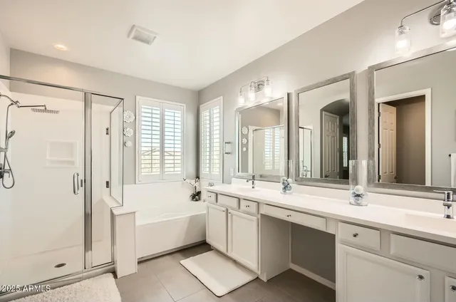 a bathroom with a double vanity sink large mirror and a bathtub