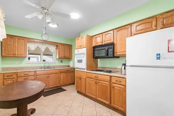 a kitchen with stainless steel appliances granite countertop a sink a stove a refrigerator a microwave oven with white cabinets and wooden floor