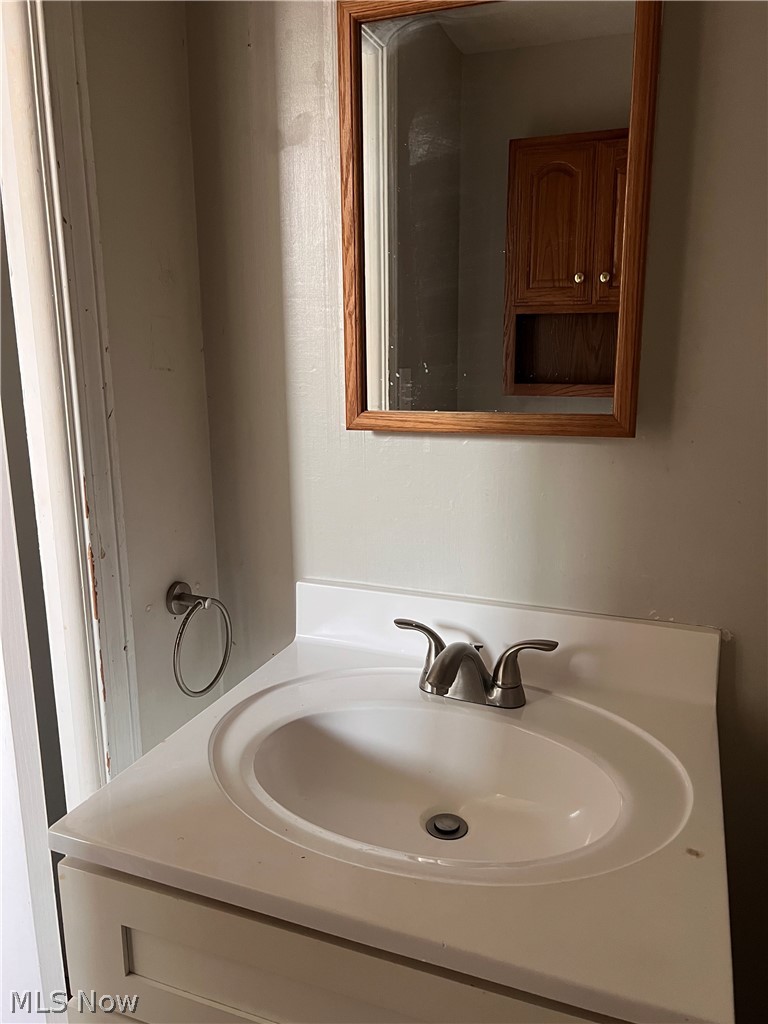 16350 Rockside Road Maple Heights, OH 44137 - Photo 13 of 34 Bathroom vanity with an integrated white sink, brushed nickel faucet, and white cabinetry