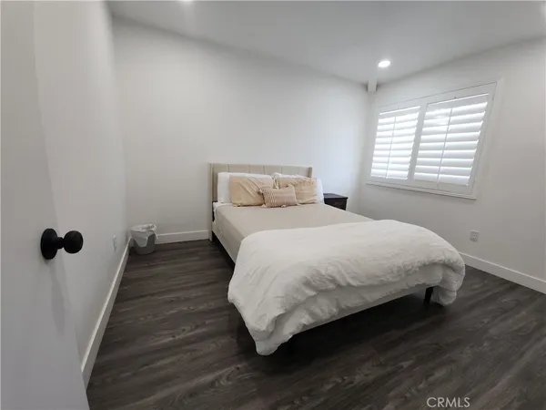 a bedroom with a bed wooden floor and window