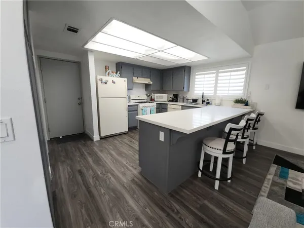 a kitchen with sink a refrigerator and wooden floor