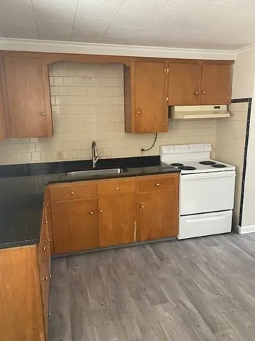 a kitchen with granite countertop a sink a stove and cabinets