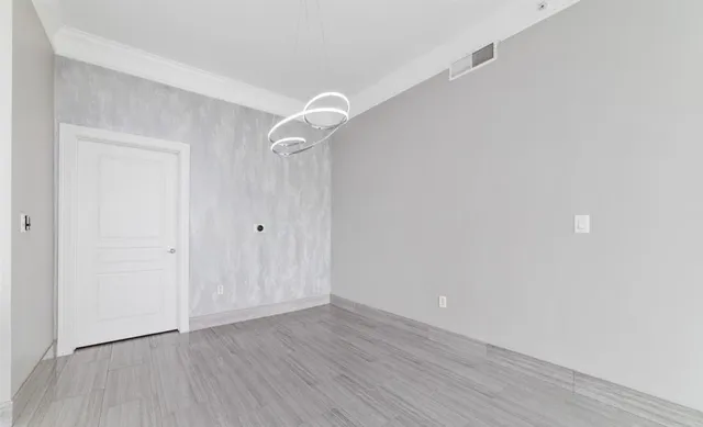 a large white kitchen with wooden floor and stainless steel appliances