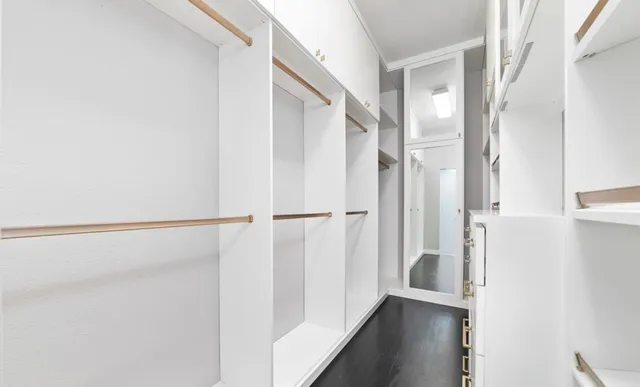 an empty room with wooden floor and windows with curtains