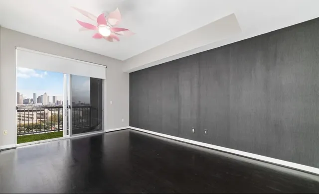 an empty room with a ceiling fan and wooden floor