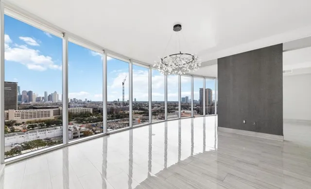 an empty room with wooden floor mirror and windows