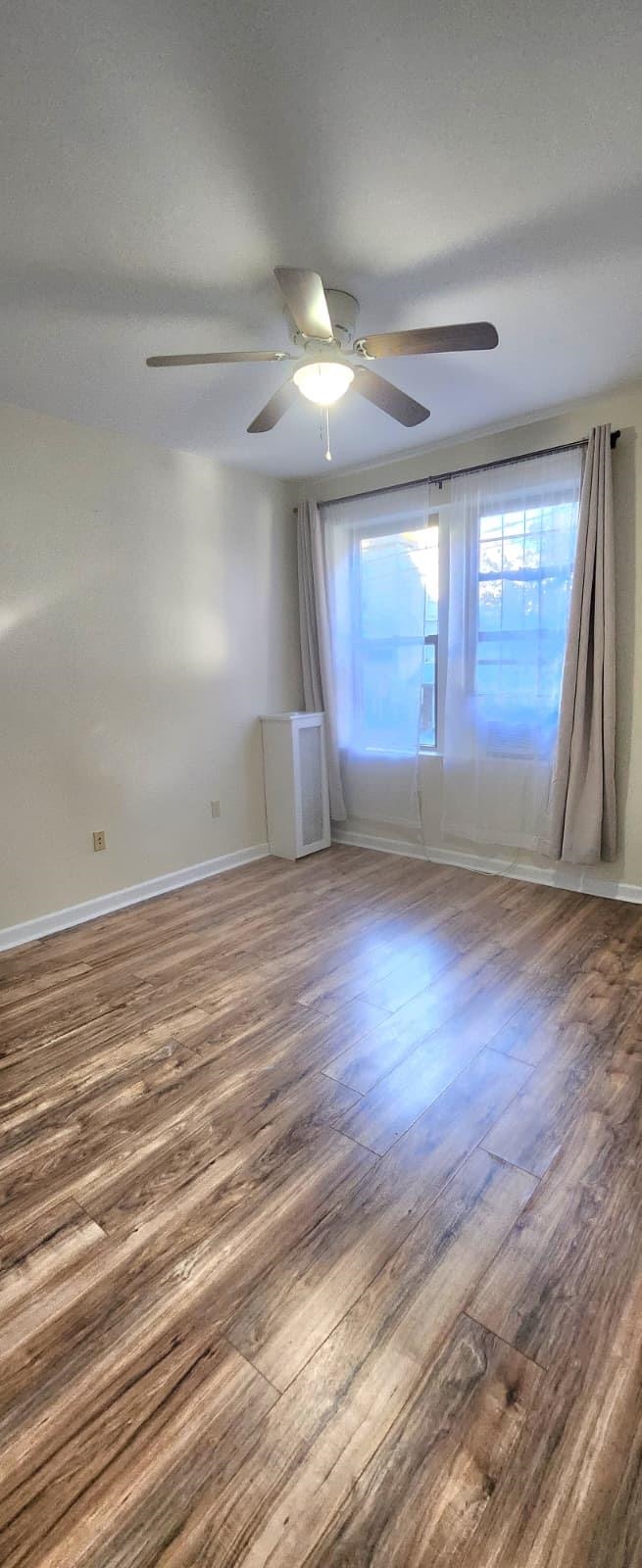 761 Avenue A, Unit 5 Bayonne, NJ 07002 - Photo 6 of 12 an empty room with wooden floor and windows