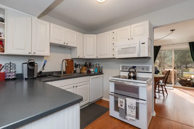 a kitchen with stainless steel appliances granite countertop a stove a sink a refrigerator and white cabinets