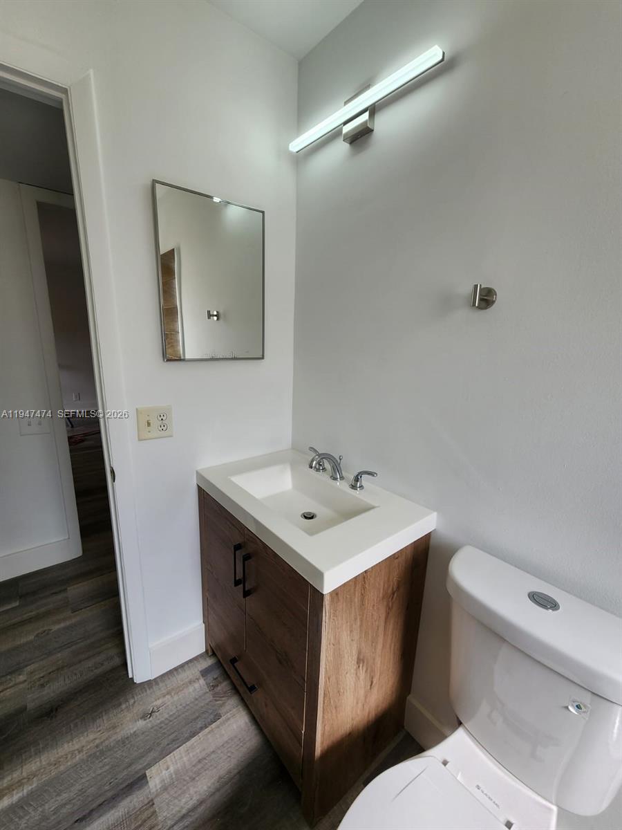 4545 Treehouse Lane, Unit H Tamarac, FL 33319 - Photo 11 of 24 a bathroom with a toilet a sink a mirror and vanity