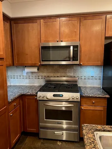 a kitchen with granite countertop cabinets stainless steel appliances and a counter space
