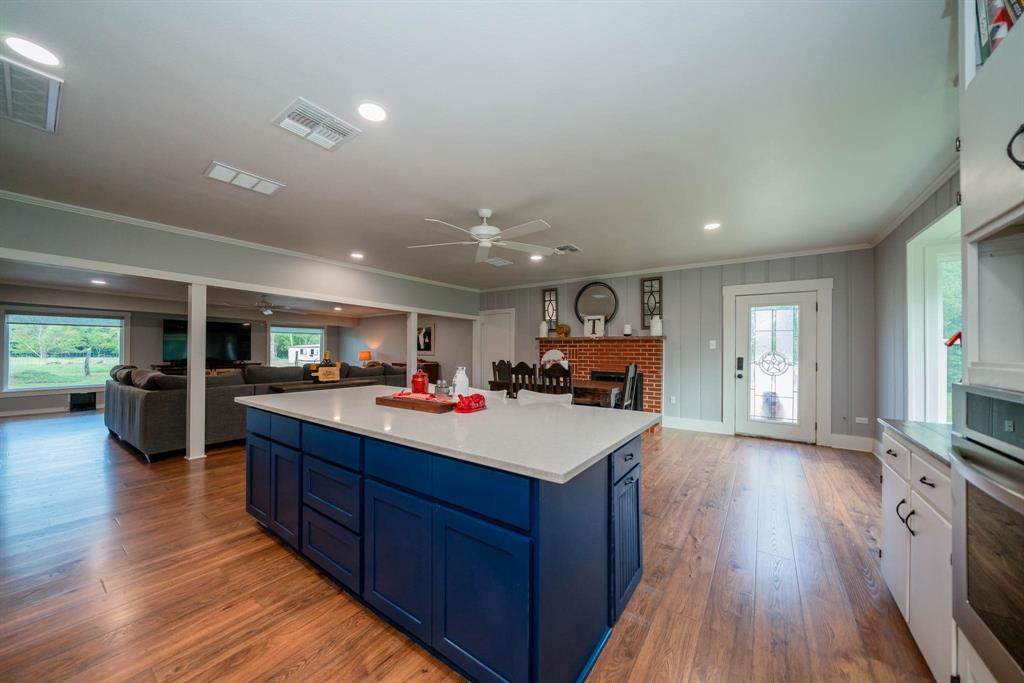 1901 Byrd Road Jacksonville, TX 75766 - Photo 39 of 40 Kitchen featuring blue cabinets, open floor plan, a brick fireplace, crown molding, and stainless steel oven