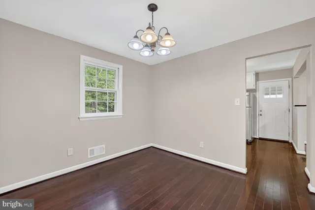an empty room with wooden floor chandelier and windows