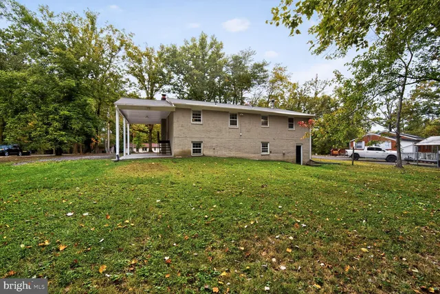 a view of a white house with a big yard and large trees