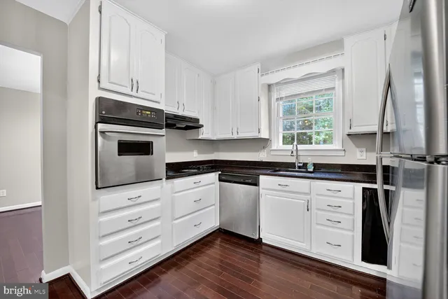 a kitchen with granite countertop white cabinets and white appliances