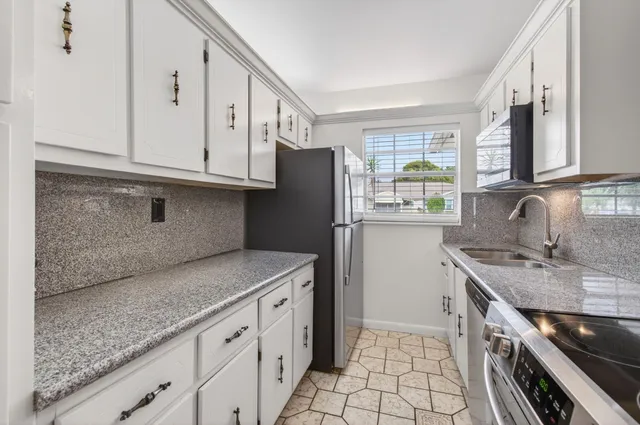 a kitchen with granite countertop a sink stove and refrigerator
