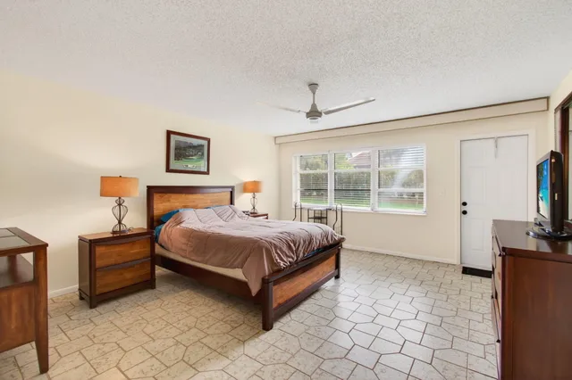 a spacious bedroom with a bed and a flat tv screen on the dresser