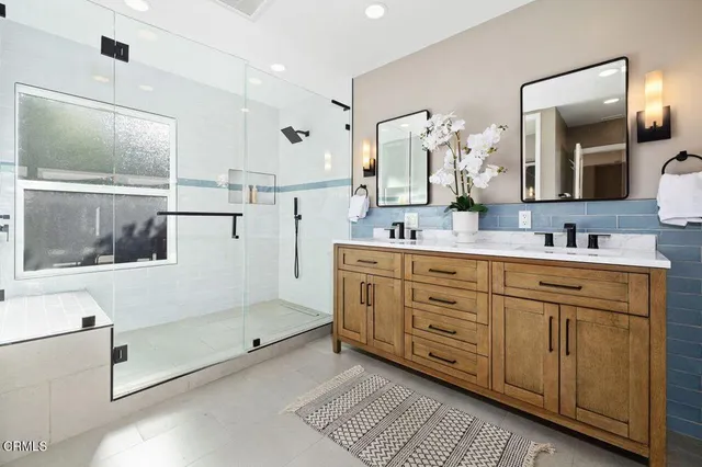 a spacious bathroom with a double vanity sink a mirror and shower