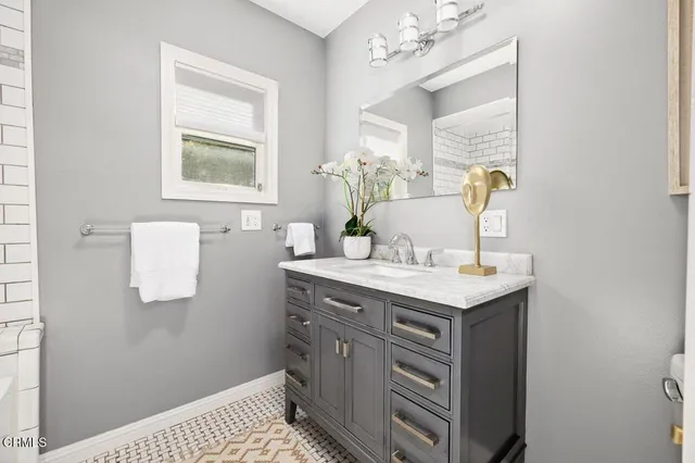 a view of bathroom with a sink mirror and window