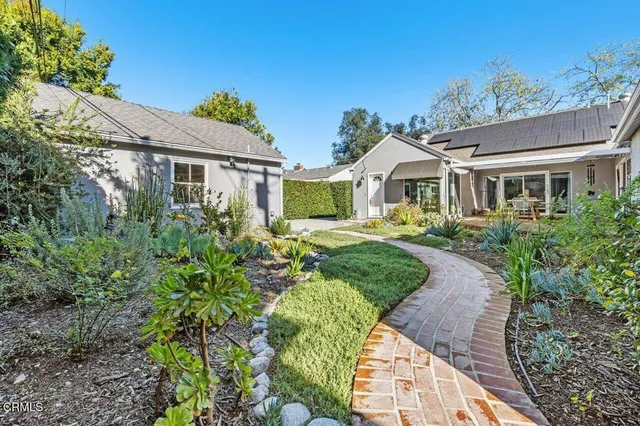 a front view of a house with a yard and potted plants