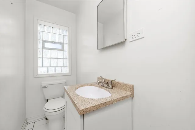 a bathroom with a granite countertop sink and a toilet