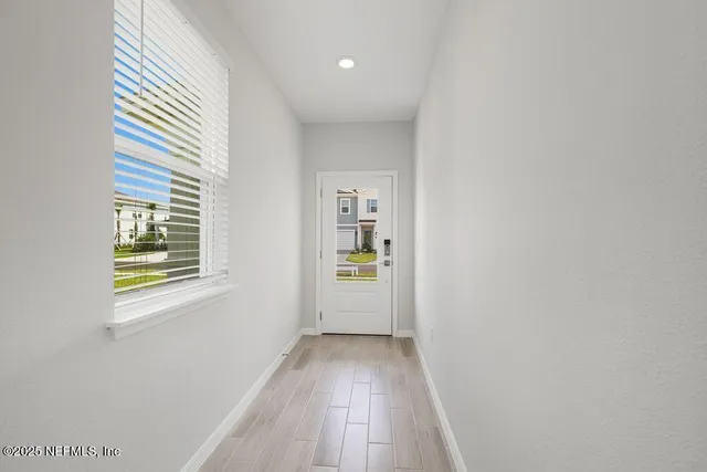 a view of a hallway with wooden floor and a window