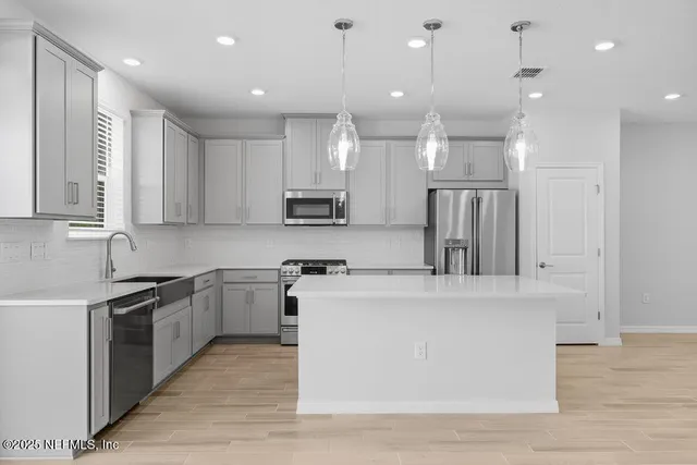 a large kitchen with stainless steel appliances granite countertop a stove a sink and a refrigerator