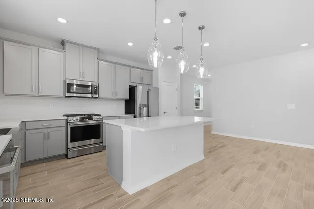 a kitchen with stainless steel appliances a stove top oven a sink and a refrigerator