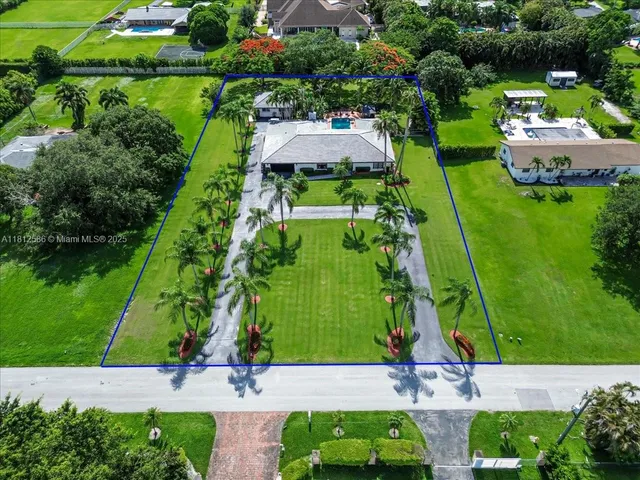 a view of house with a big yard and palm trees