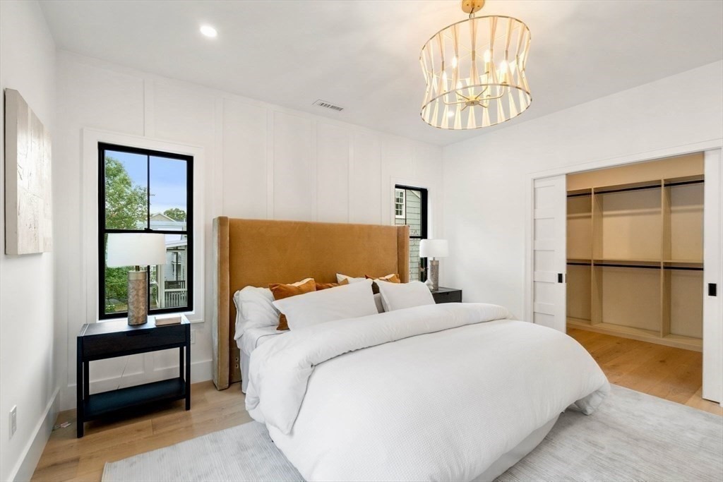 71 Cloverdale Road, Unit 1 Newton, MA 02461 - Photo 25 of 32 a bedroom with a large bed and a chandelier