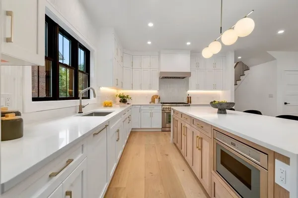 a large kitchen with a large counter top a sink stainless steel appliances and cabinets