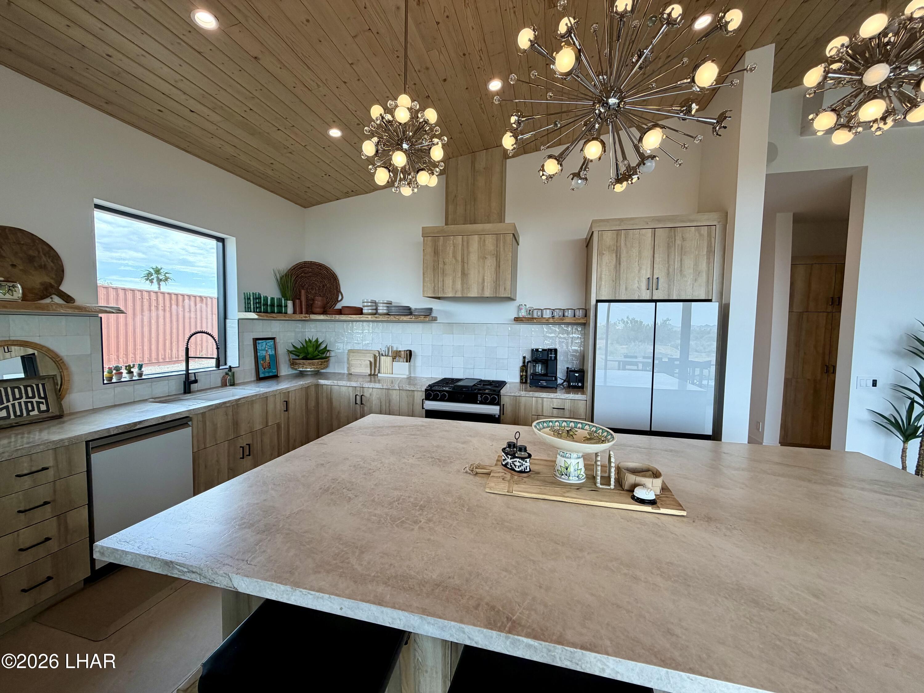 48963 Riviera Place Ehrenberg, AZ 85334 - Photo 20 of 58 a kitchen with kitchen island granite countertop a stove a sink a refrigerator and a dining table