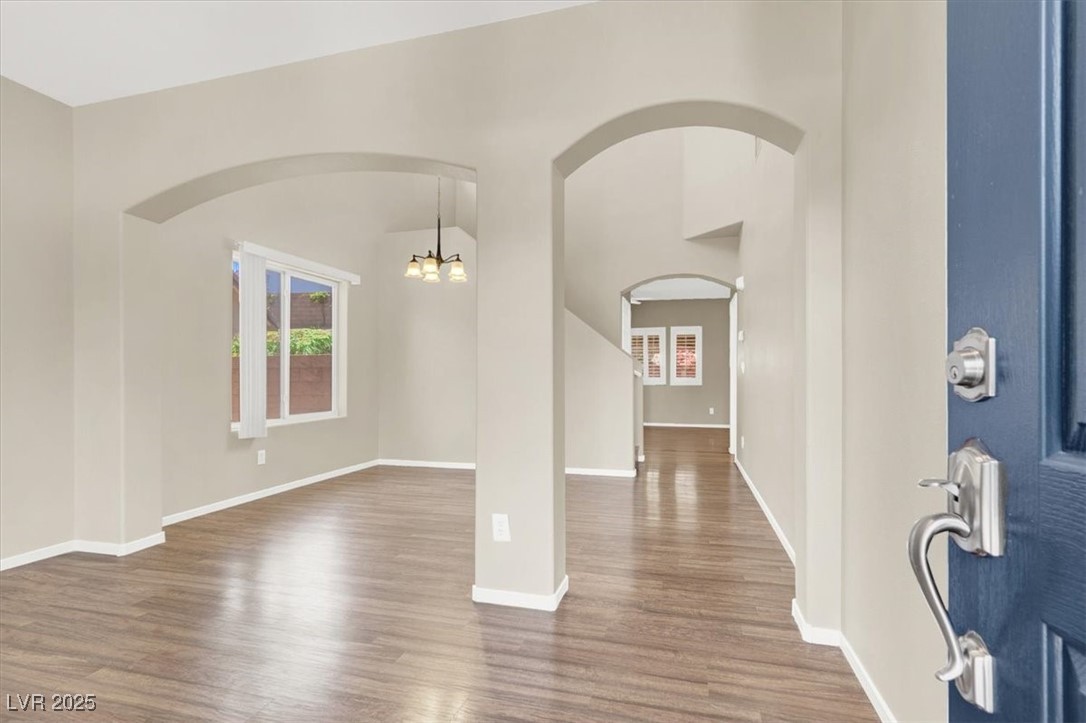 636 Pacific Cascades Drive Henderson, NV 89012 - Photo 12 of 51 Foyer featuring arched walkways, wood finished floors, a chandelier, and healthy amount of natural light