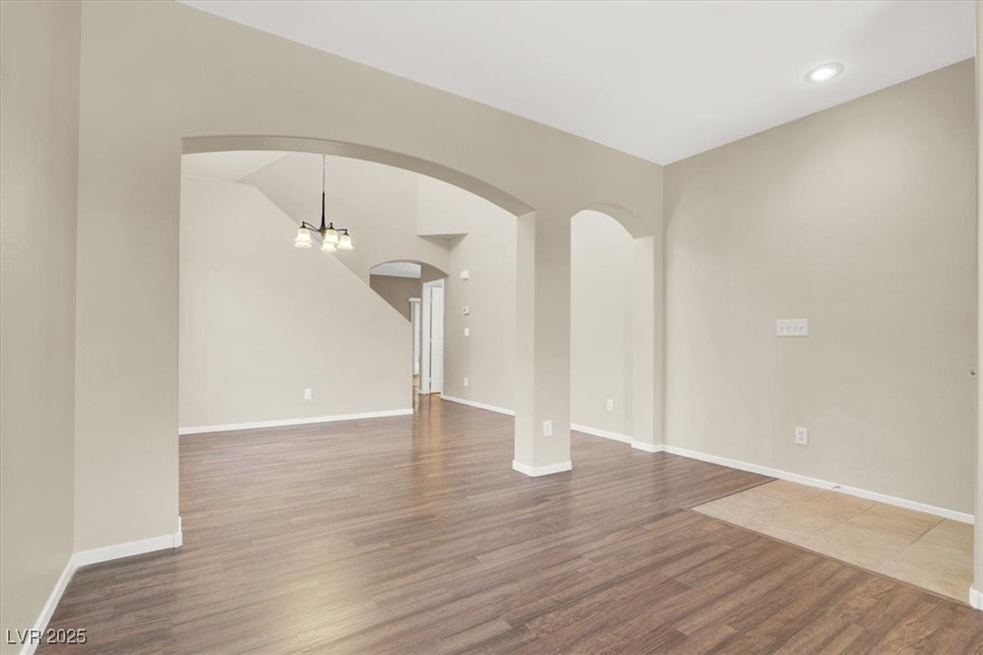 636 Pacific Cascades Drive Henderson, NV 89012 - Photo 14 of 51 Unfurnished living room featuring dark wood-type flooring and a chandelier