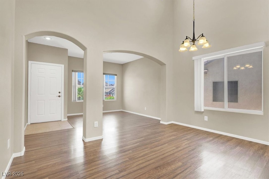 636 Pacific Cascades Drive Henderson, NV 89012 - Photo 4 of 51 Spare room featuring light wood-style flooring, a high ceiling, arched walkways, and a chandelier