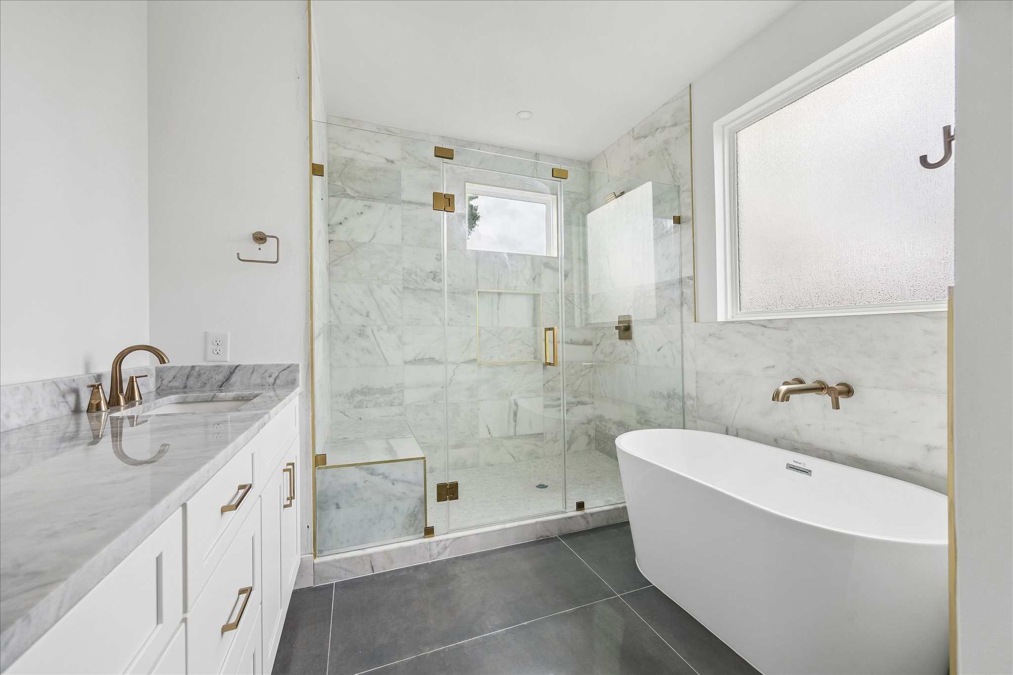 1034 West 17th Street, Unit B Houston, TX 77008 - Photo 9 of 25 Spa-like primary bath with a luxurious soaking tub, glass-enclosed shower with bench seating, dual sinks, and dolomite countertops.