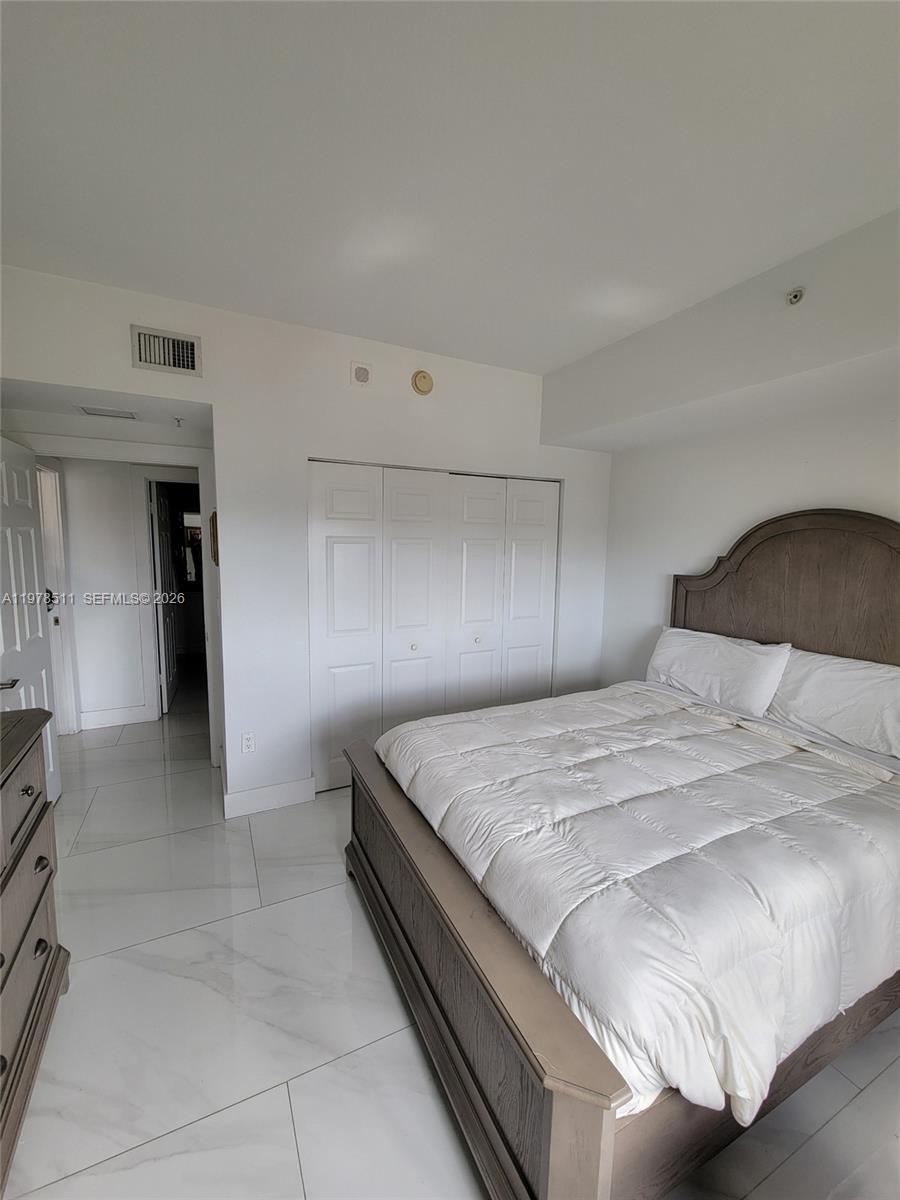 888 Douglas Road, Unit 1110 Coral Gables, FL 33134 - Photo 18 of 28 a bedroom with a bed and a lamp