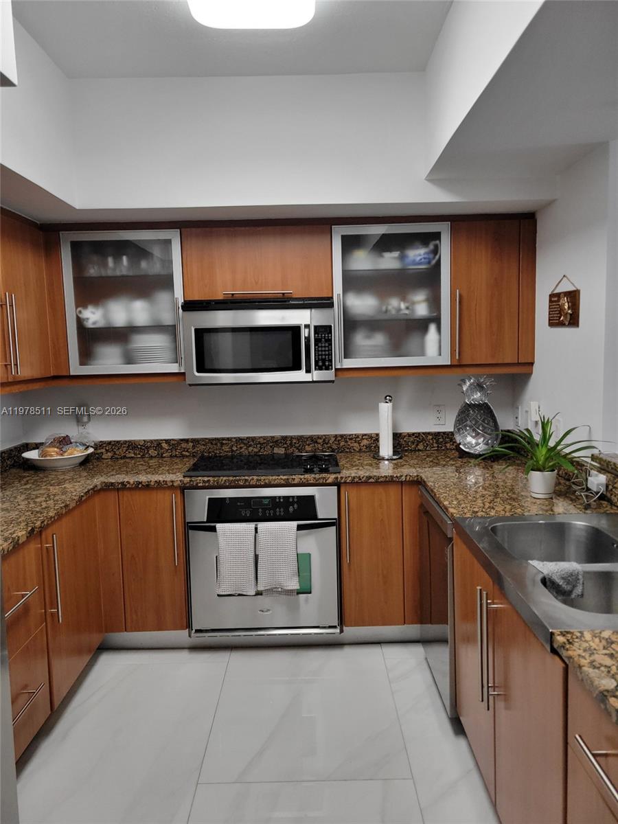 888 Douglas Road, Unit 1110 Coral Gables, FL 33134 - Photo 5 of 28 a kitchen with stainless steel appliances granite countertop a sink stove and microwave