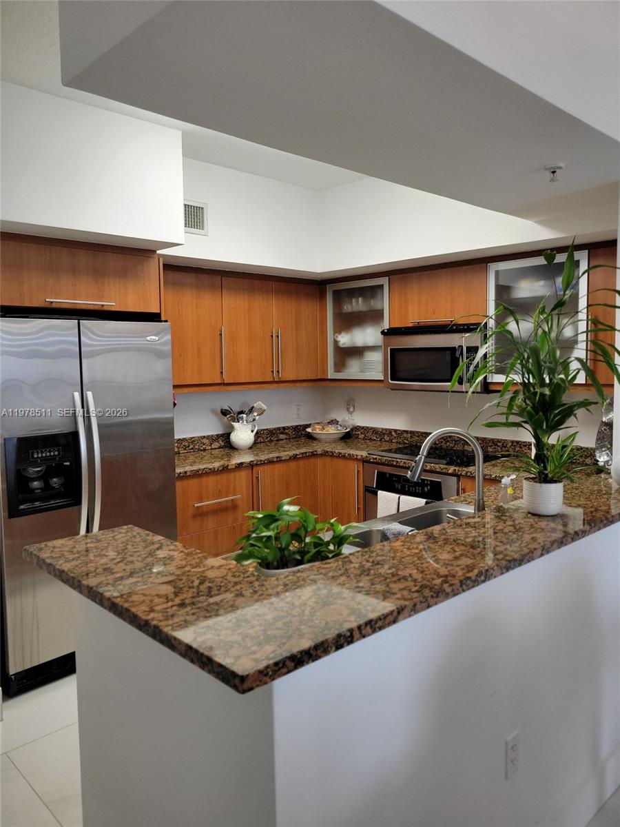 888 Douglas Road, Unit 1110 Coral Gables, FL 33134 - Photo 6 of 28 a kitchen with stainless steel appliances granite countertop a sink a stove and a microwave